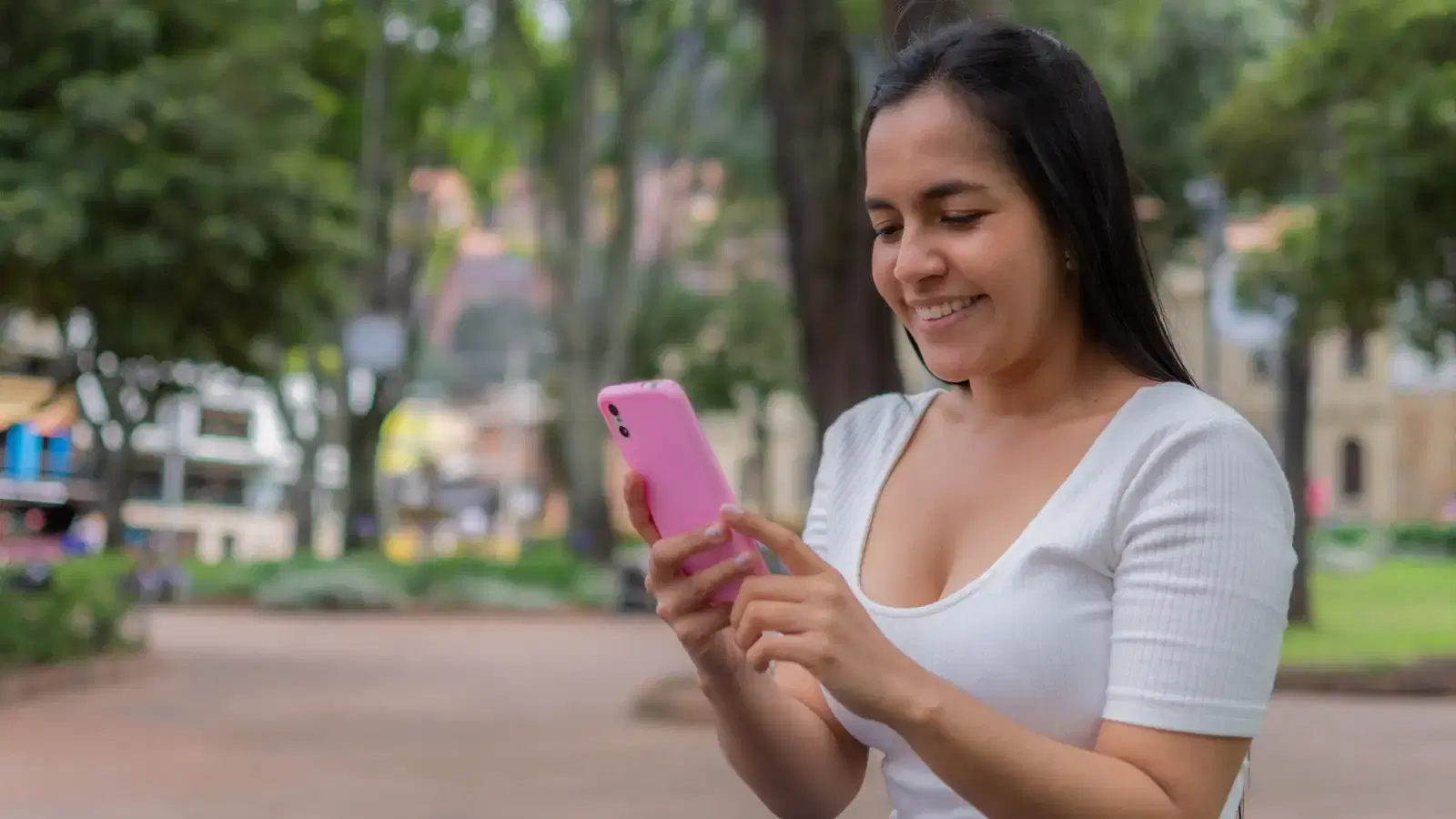 Mujer sonriente usa su celular en un parque